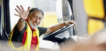 Happy courier greeting and waving at someone